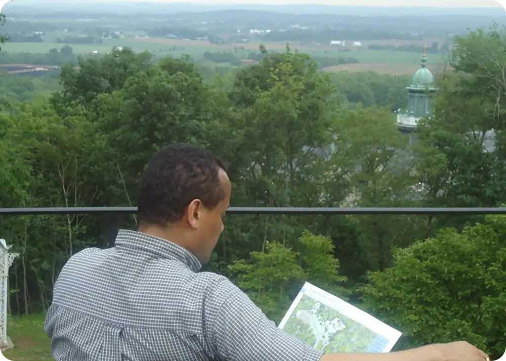 Person reading map on balcony overlooking countryside