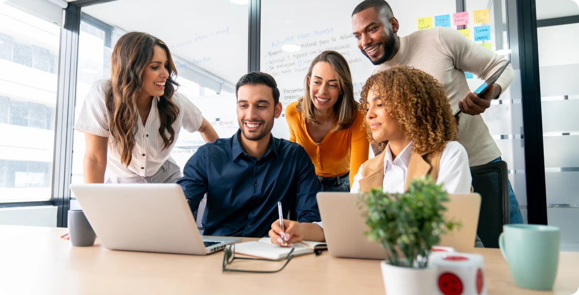 Diverse team collaborating around laptops in office